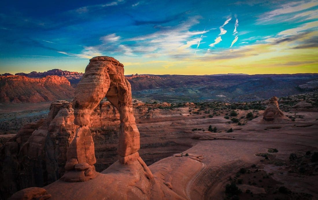 a natural sandstone arch formation in Arches National Park Utah with a sunset in the background