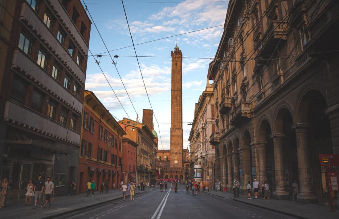 People walking toward Asinelli tower in bologna italy in the late afternoon.