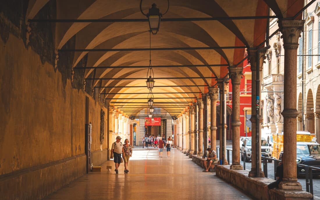 A couple walking under one of the porticos of bologna italy 