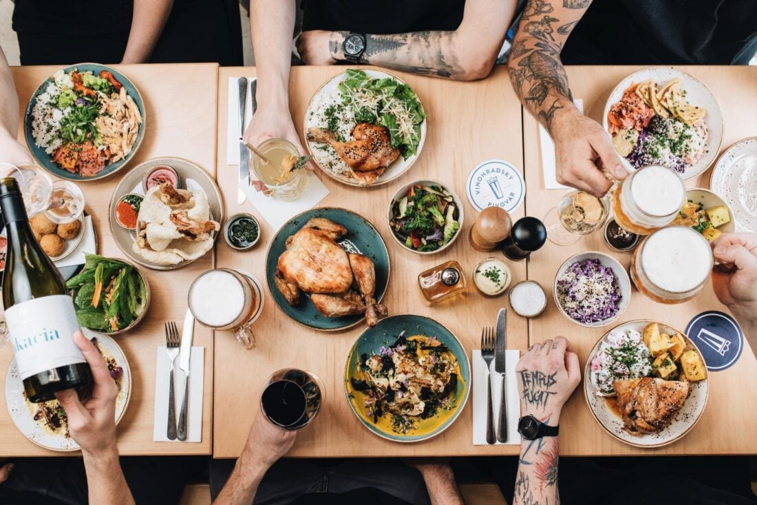 A table spread iwth a rotisserie chicken surrounded by drinks and side dishes at Kro, the best Prague alternative for rotisserie chicken from your local deli.