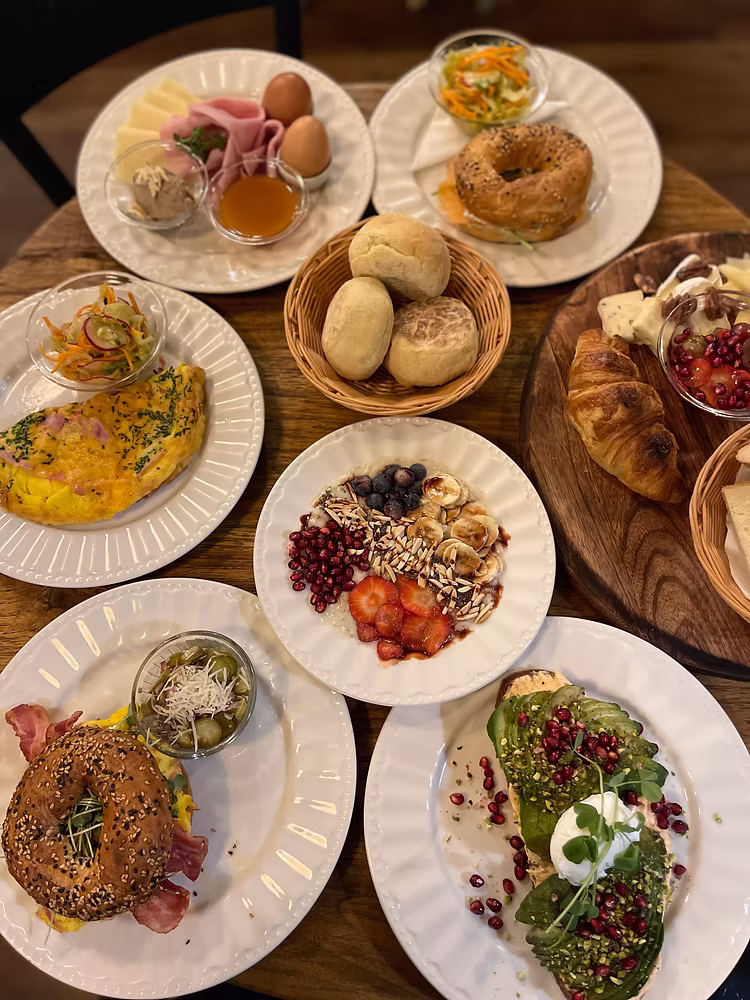 A brunch spread with avocado toast, a granola bowl, a bagel sandwich, and more at Marthy's Kitchen. 