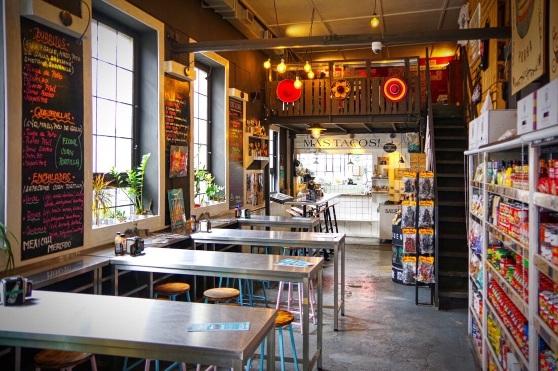 The taco bar at Mexicali Mercado with sliver tables and Mexican decor.